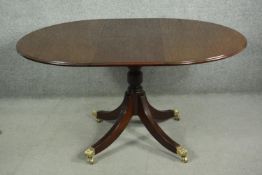 A reproduction Georgian style mahogany dining table, of circular form, with an additional leaf, on