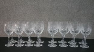 Two sets of eight cut crystal wine glasses with stylised foliate design, each set with a different