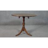 An early 19th century country oak tilt top table on swept tripod supports. H.66 Diam.74cm