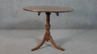 An early 19th century country oak tilt top table on swept tripod supports. H.66 Diam.74cm