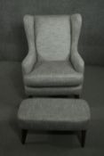 A contemporary wing back armchair and foot stool, upholstered in light grey fabric, on tapering