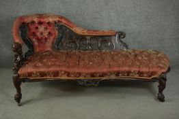 A Victorian rosewood rococo revival chaise longue, upholstered in foliate patterned red silk with