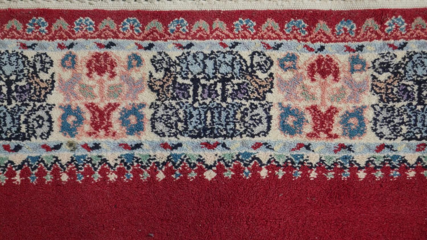 A hand made Moroccan rug with central floral medallion on a burgundy ground within a foliate border. - Image 5 of 9