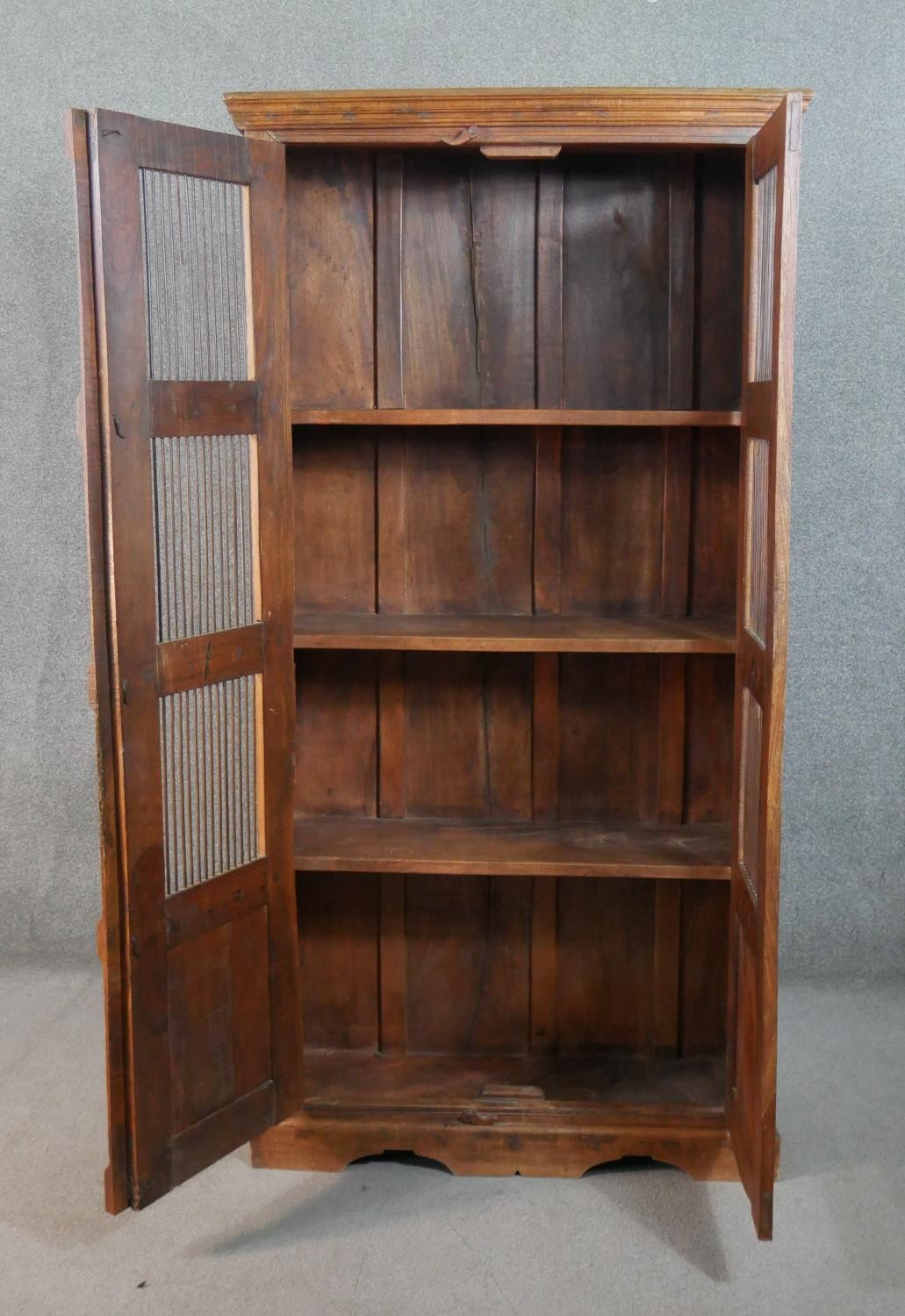 A 20th century Indian sheesham bookcase, the two doors with metal spindle panels, opening to - Image 5 of 8