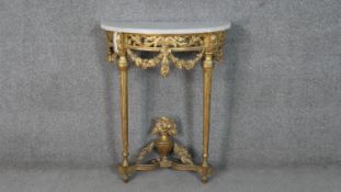 A carved gilt console table with demi lune marble top above fluted tapering supports and all over