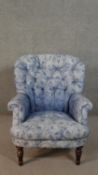 A Victorian style armchair, with button back, upholstered in blue fabric with flowerheads, on turned