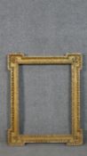 A large giltwood picture frame with floral motifs to the corners. H.80 W.65cm, recess: H.61 W.50cm.