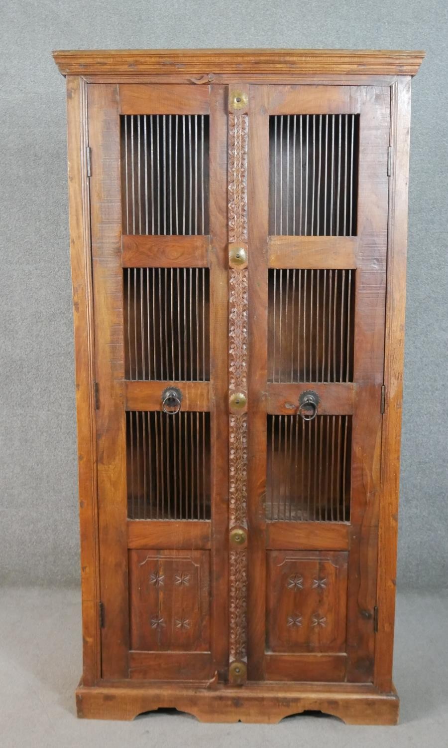 A 20th century Indian sheesham bookcase, the two doors with metal spindle panels, opening to