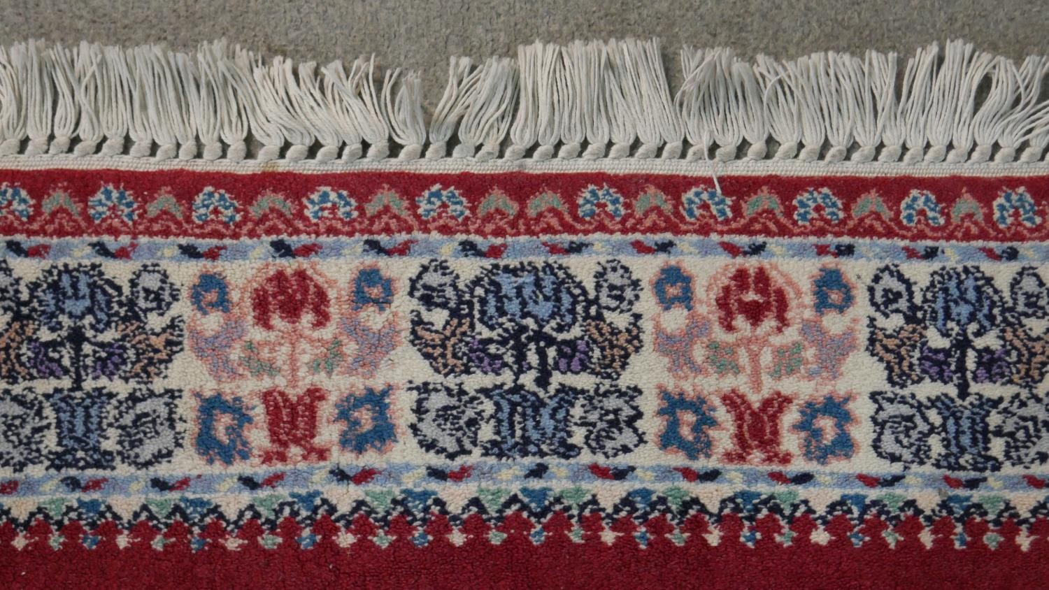 A hand made Moroccan rug with central floral medallion on a burgundy ground within a foliate border. - Image 7 of 9