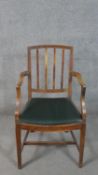An oak Hepplewhite style open armchair, with a spindle back over a green faux leather seat, on