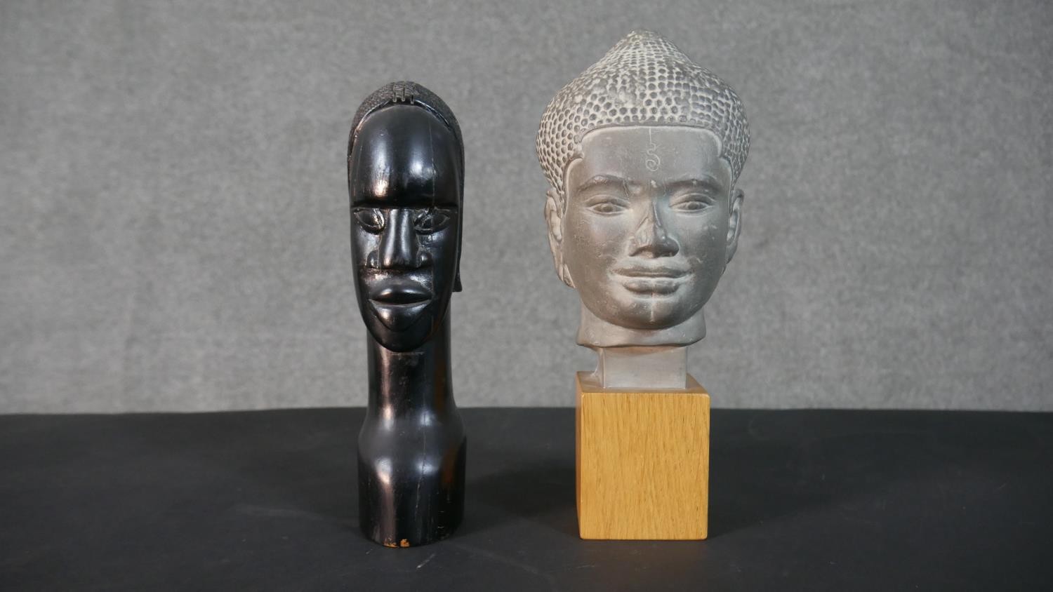 Two bust figures, one tribal carved hardwood and the other a Louvre Museum replica of an Angkor