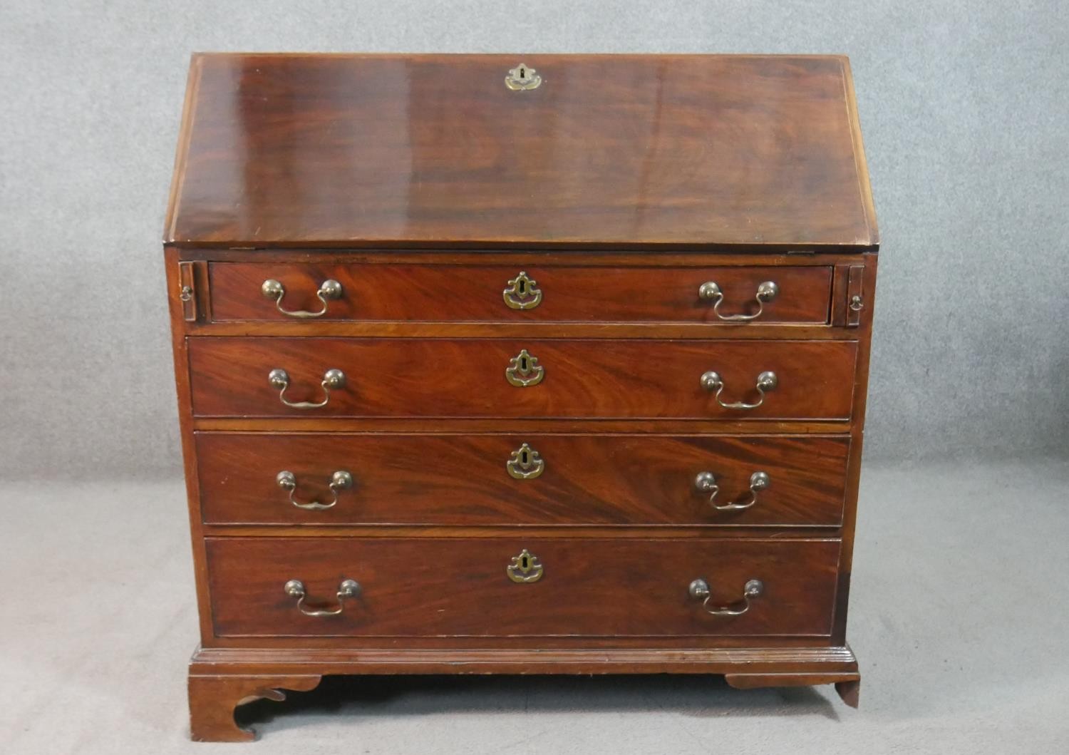 A George III mahogany bureau, the fall front opening to reveal a central cupboard door, drawers