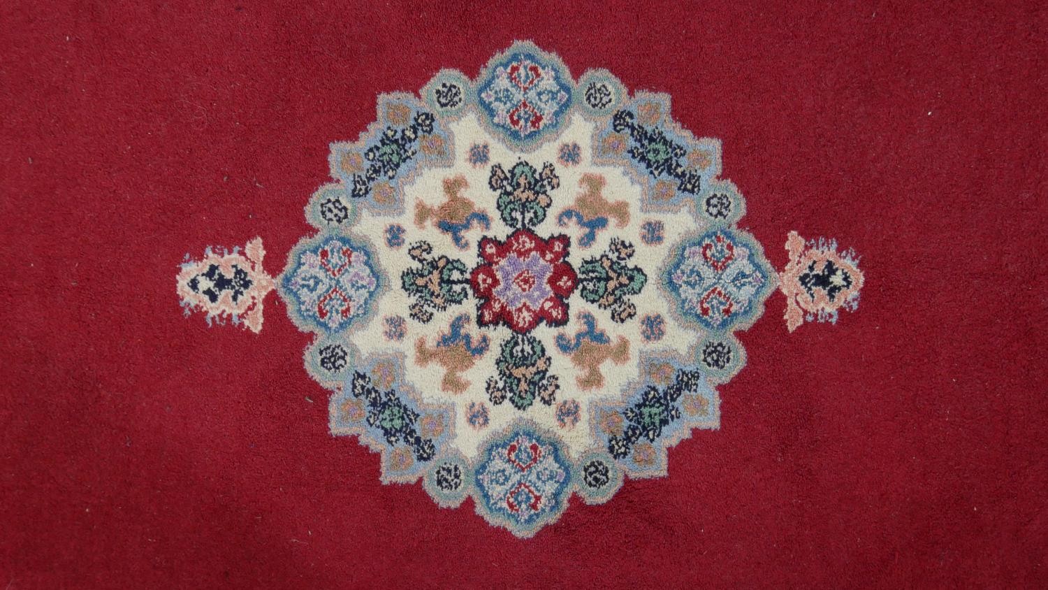 A hand made Moroccan rug with central floral medallion on a burgundy ground within a foliate border. - Image 3 of 9