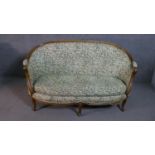 A French Louis XVI style walnut framed canape sofa, with a curved back, upholstered in a printed