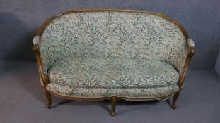 A French Louis XVI style walnut framed canape sofa, with a curved back, upholstered in a printed