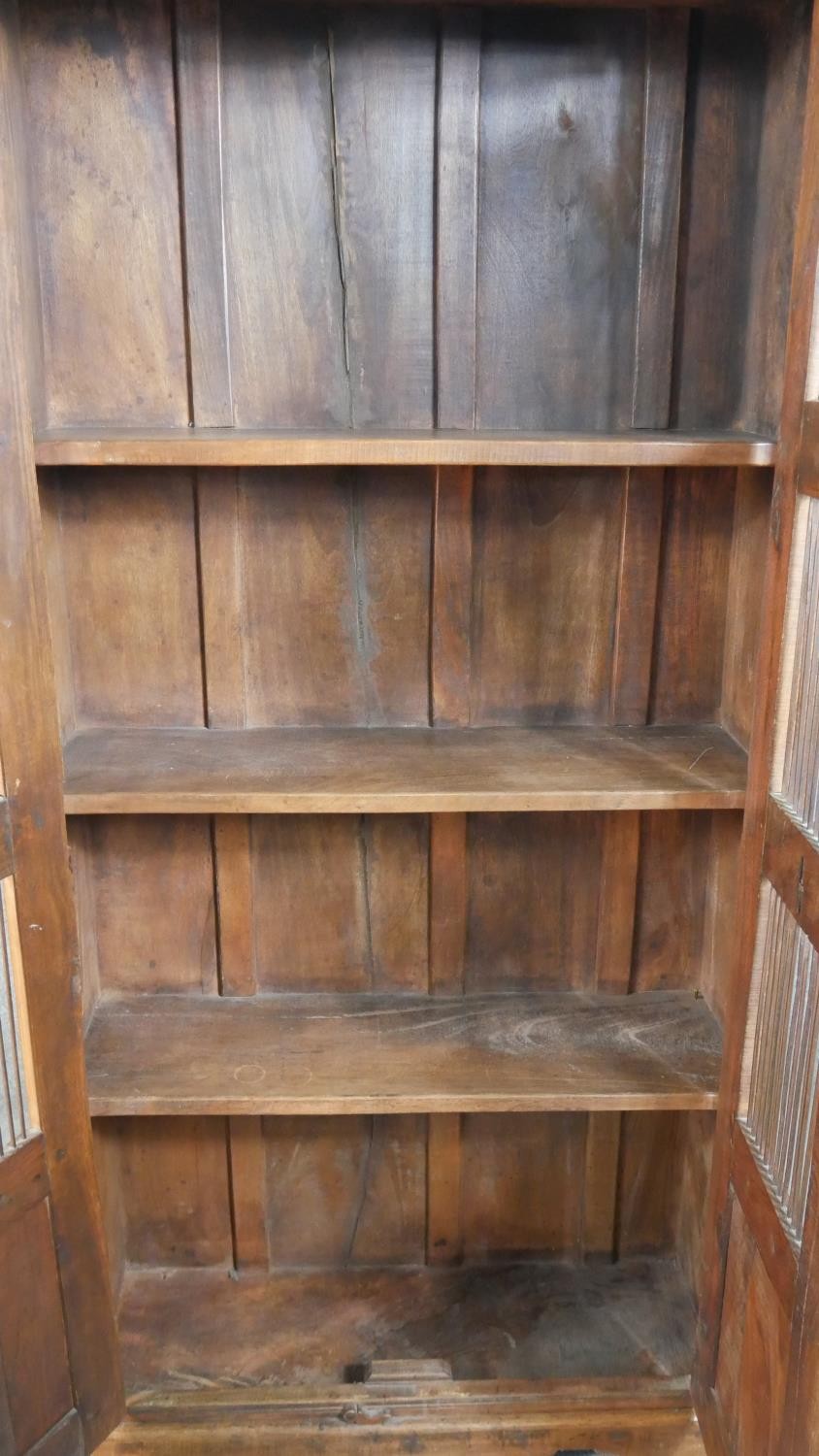 A 20th century Indian sheesham bookcase, the two doors with metal spindle panels, opening to - Image 6 of 8