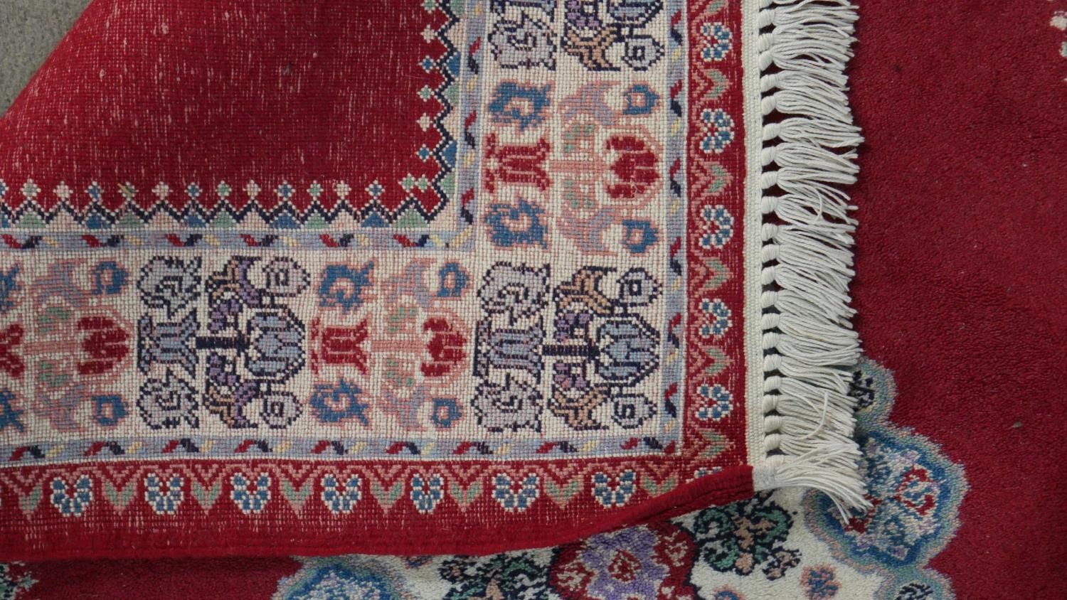 A hand made Moroccan rug with central floral medallion on a burgundy ground within a foliate border. - Image 8 of 9