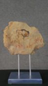 A slice of rock with hand painted cave painting depicting a bison and hunters. Mounted on metal rods