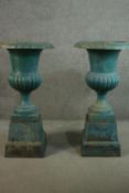 A large pair of 19th century green painted cast iron urns of campana form with flared rims on