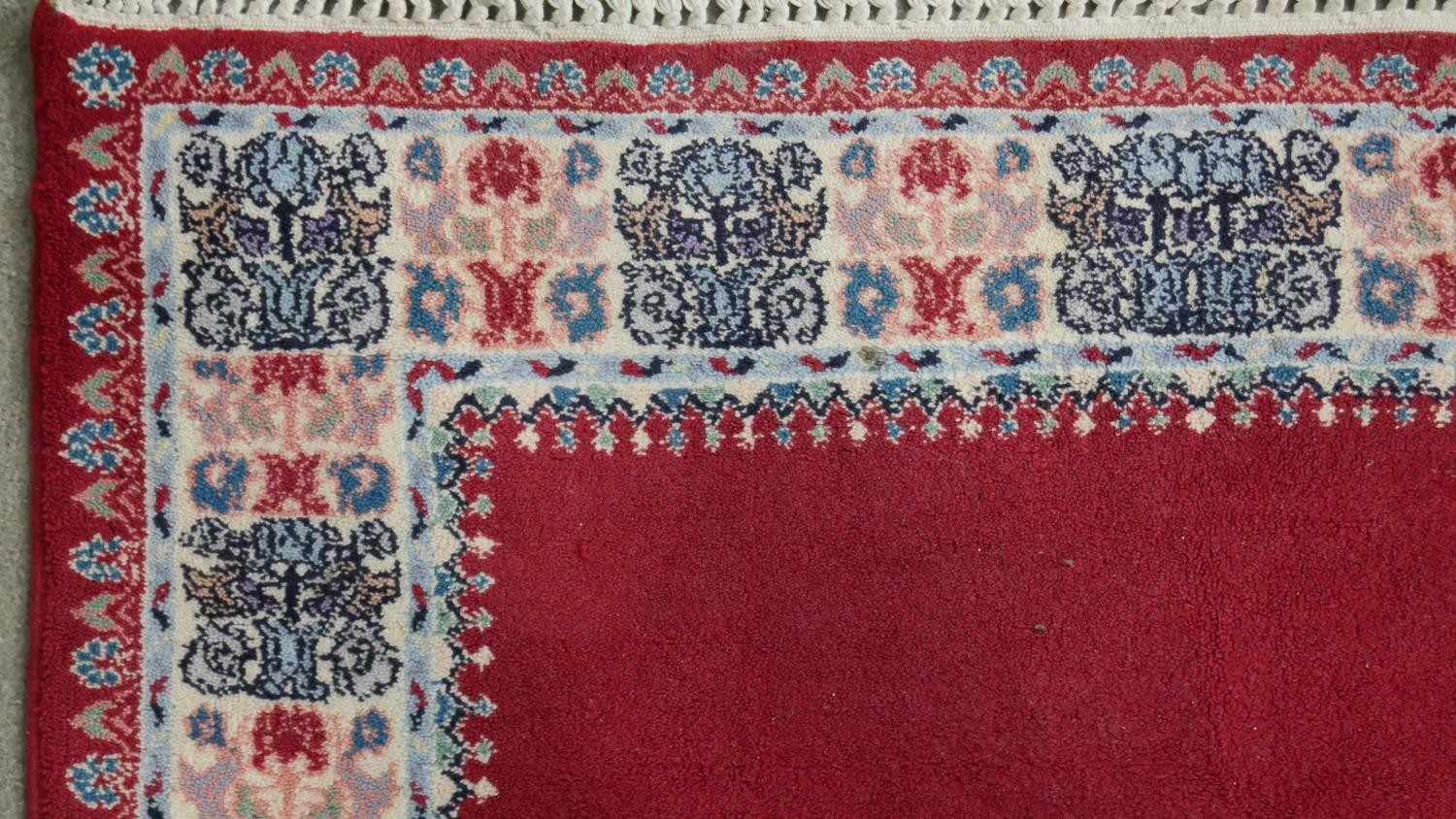A hand made Moroccan rug with central floral medallion on a burgundy ground within a foliate border. - Image 4 of 9