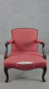 A 19th century mahogany open armchair, upholstered in crimson coloured fabric, the scrolling arms