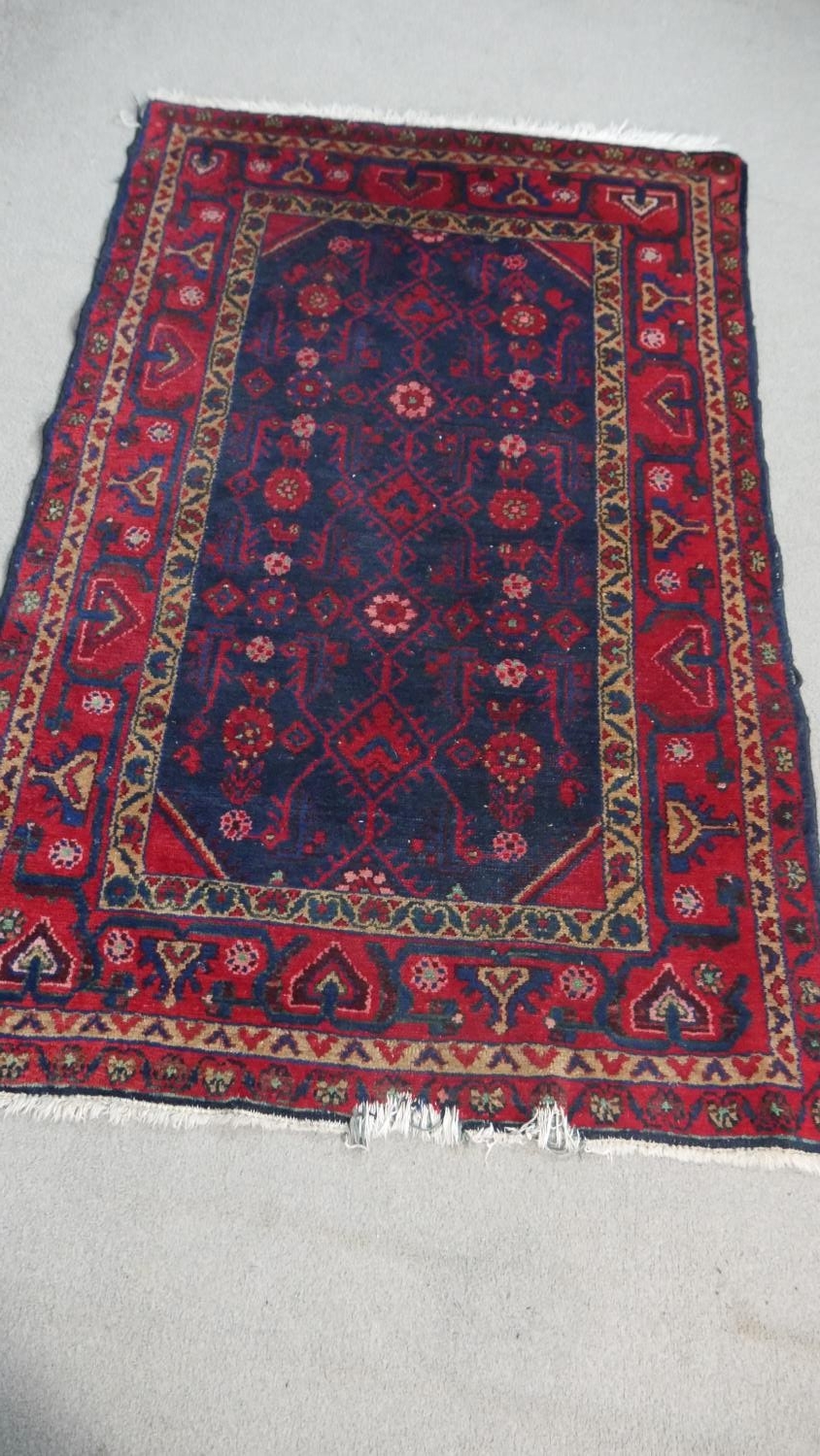 A Persian Hamadan rug with stylised hooked design on a midnight ground. L.170 W.110cm