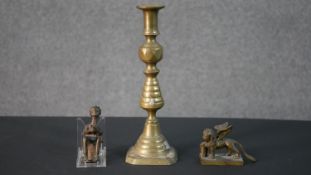 A 19th century brass candlestick along with an African bronze figure and a brass winged lion