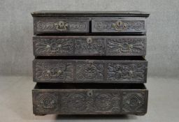 An 18th century oak chest of two short over three long graduated drawers, all ornately carved, on
