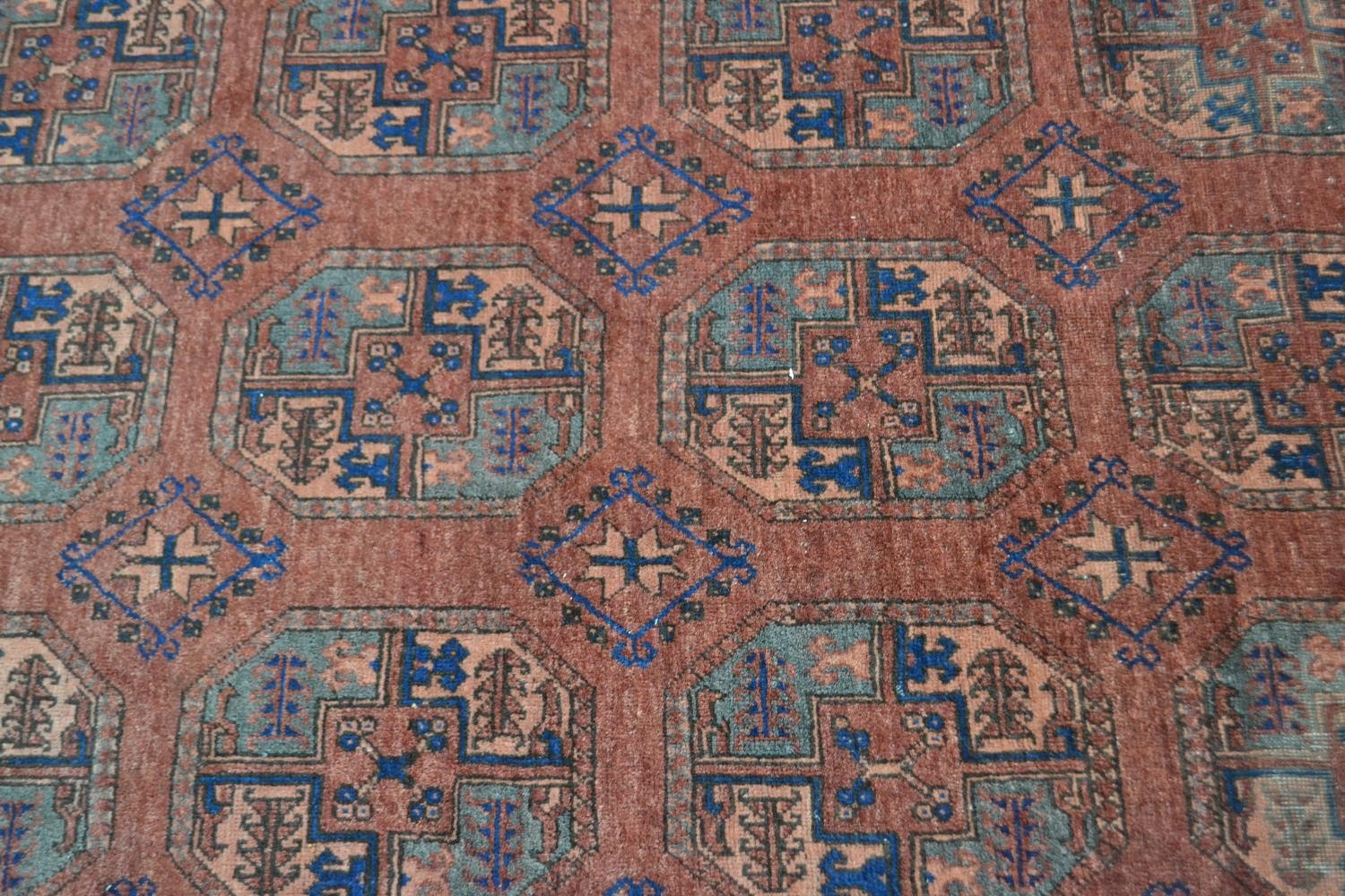 A handmade Afghan carpet with repeating gul motifs on a burgundy field within stylised borders. L. - Image 3 of 7