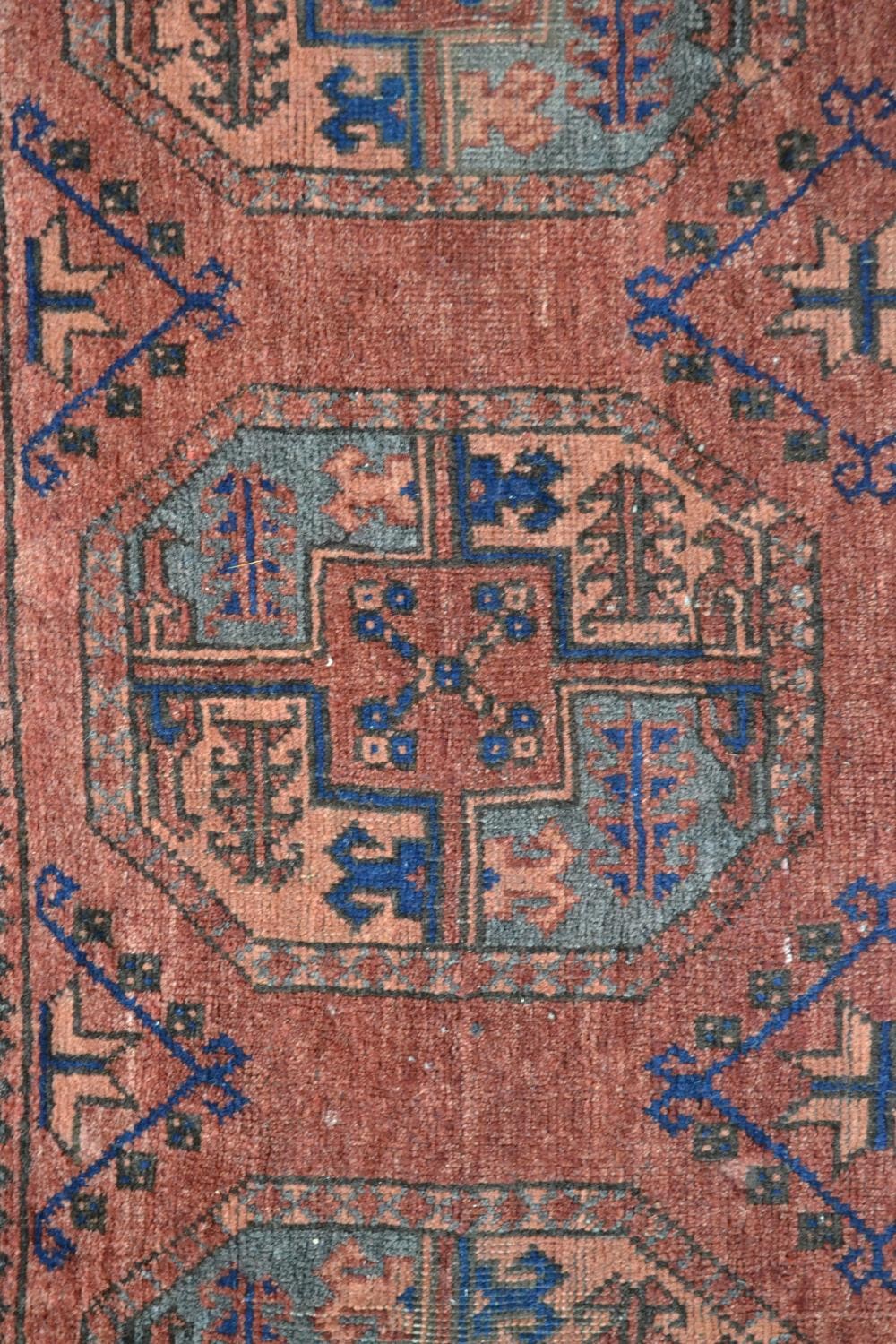 A handmade Afghan carpet with repeating gul motifs on a burgundy field within stylised borders. L. - Image 5 of 7