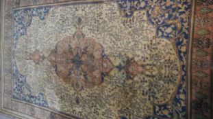 A Persian style carpet with central medallion and tree of life motifs on a biscuit ground