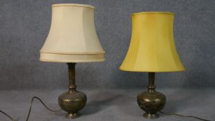 A pair of Indian engraved brass vases converted into table lamps, each with a figural design. H.60cm