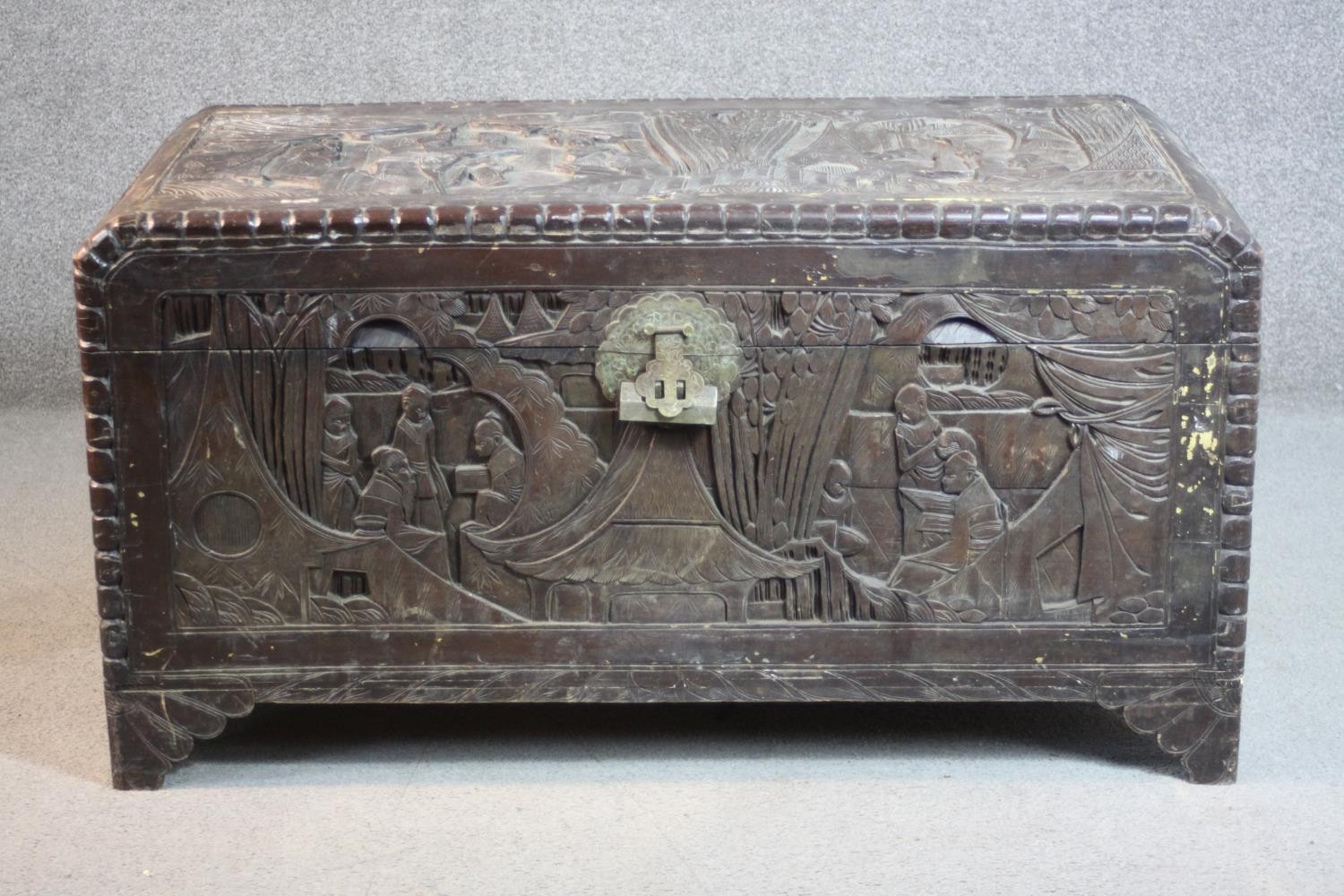 An early 20th century Chinese camphorwood chest, the exterior carved allover with figures amongst