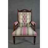 A late Victorian walnut armchair, upholstered in ivory, pink, blue and green striped fabric with a