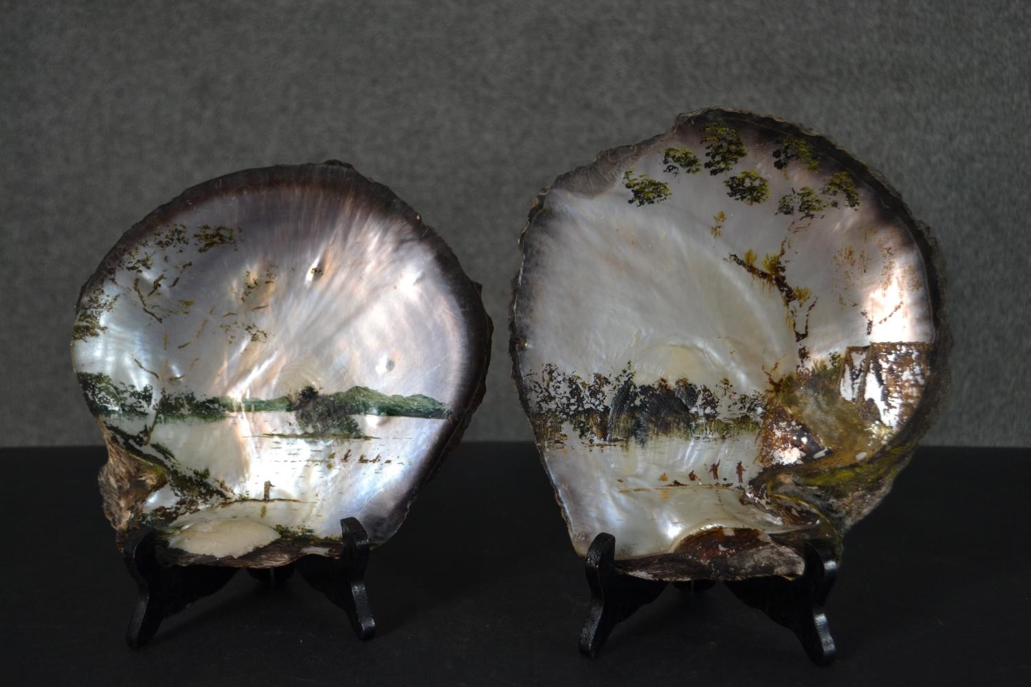 Two 19th century painted oyster shells on wooden stands, each depicting a Japanese mountain lake