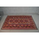 A hand made Afghan Kelim carpet with repeating medallions on a rouge ground. L.236 W.154cm