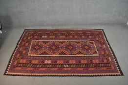 A hand made Afghan Kelim carpet with repeating medallions on a rouge ground. L.236 W.154cm