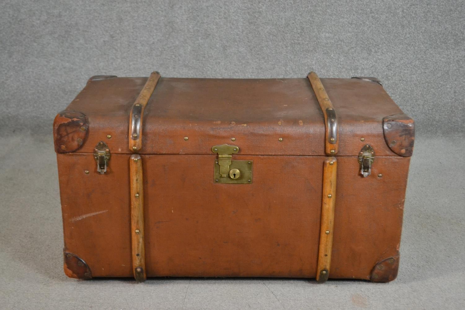 An early 20th century brown travel trunk, with wood bracing and brown leather corners. (locked) H.42