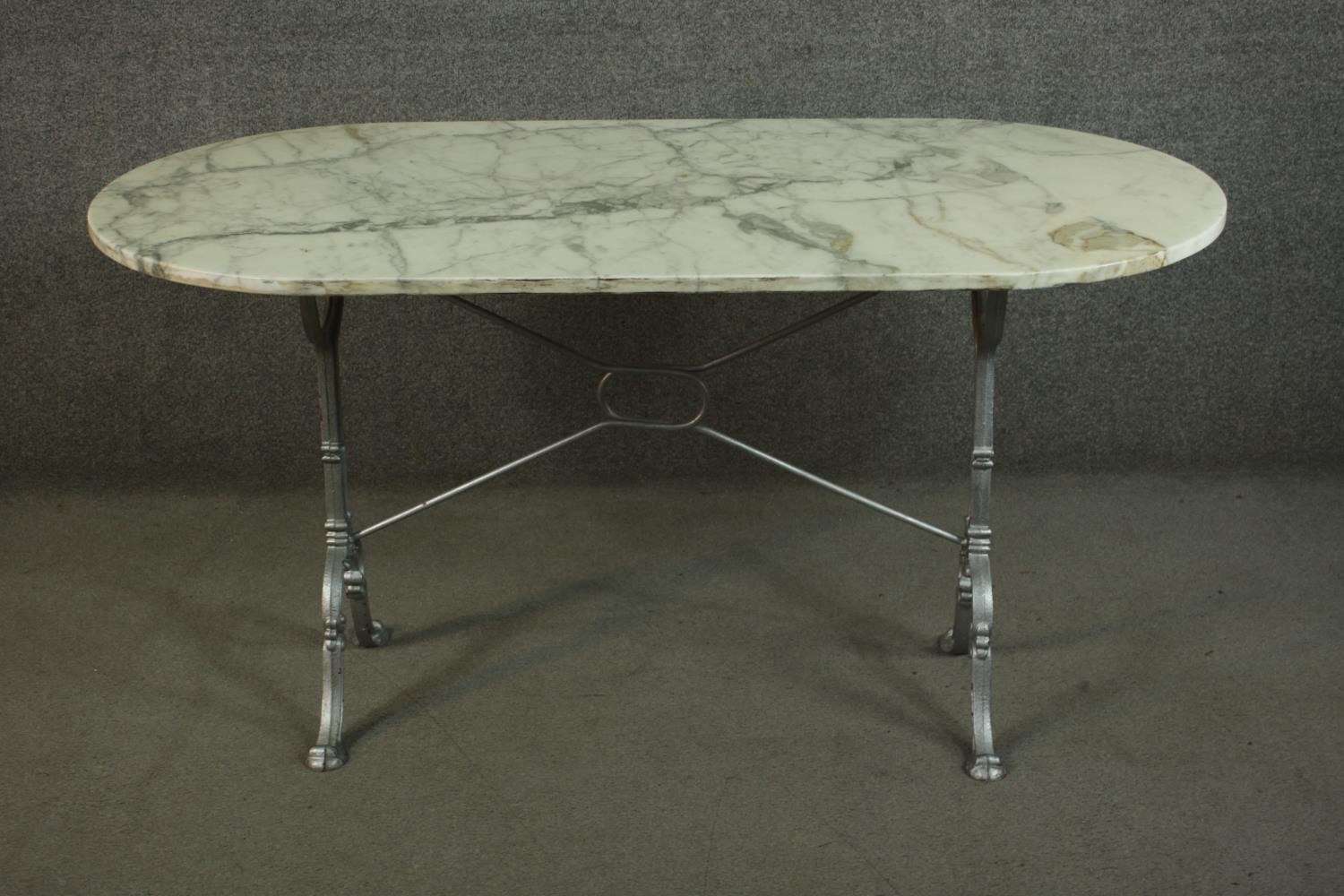 An Italian marble topped cast iron table, the top with rounded ends, on cast end supports, joined by