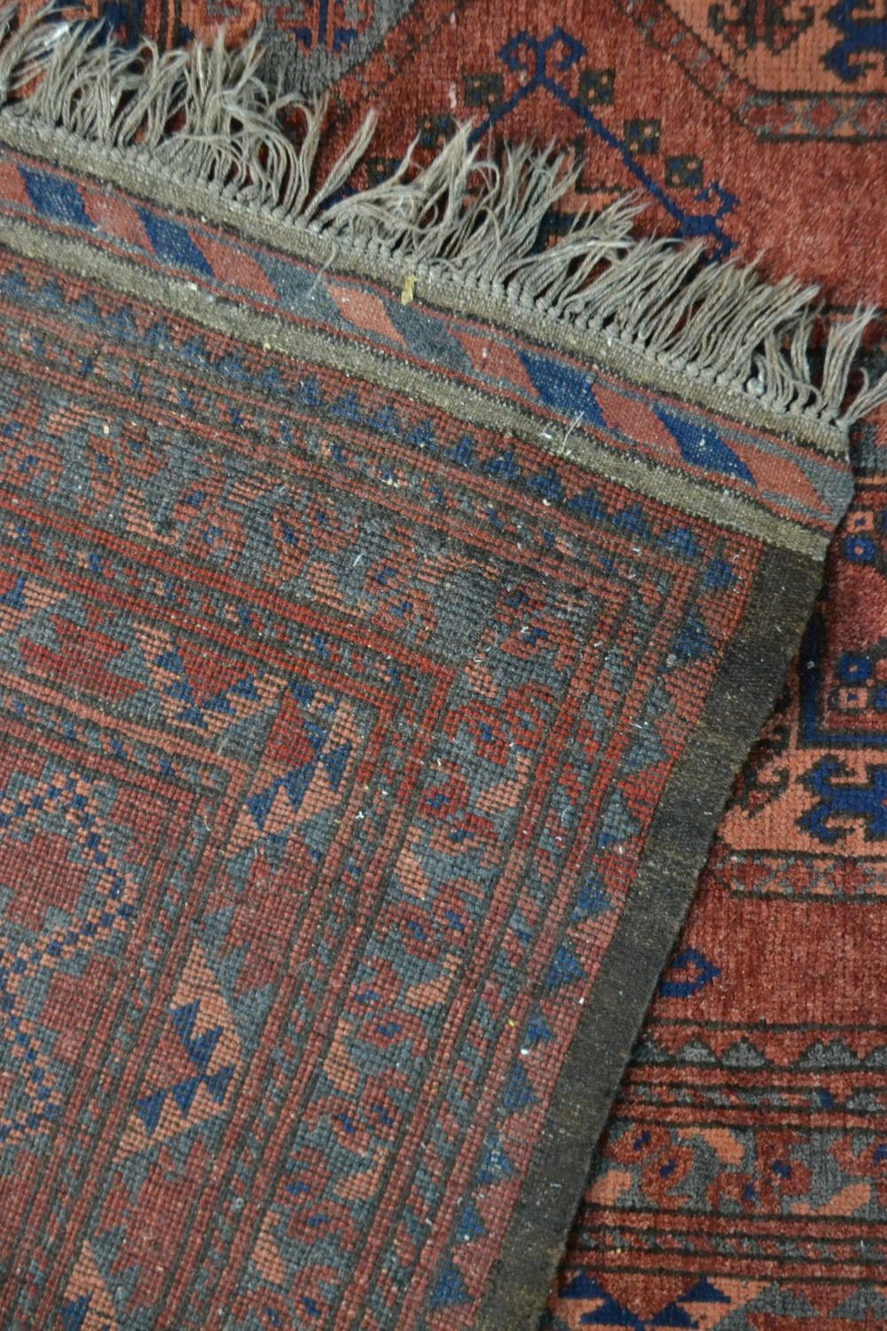 A handmade Afghan carpet with repeating gul motifs on a burgundy field within stylised borders. L. - Image 7 of 7