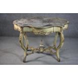 An Italian painted and parcel gilt centre table, of cartouche form, with a leather insert, above a