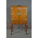 An Epstein style 1930s burr walnut drinks cabinet, the two cupboard doors with ornate brass