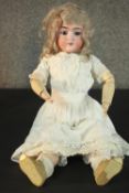 A Victorian porcelain doll by König & Wernicke with glass eyes, lace dress and wooden jointed limbs.