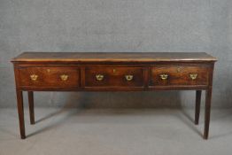 A mid 18th century oak dresser base, the three short drawers with brass swing handles on brass