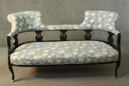 A circa 1900 ebonised sofa, upholstered to the back rail and seat with grey fabric decorated with