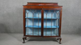 An early 20th century bow front mahogany display cabinet, the gallery back and top both with