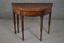 A George III mahogany demi-lune tea table, the fold over top over reeded and cylindrical legs. H.