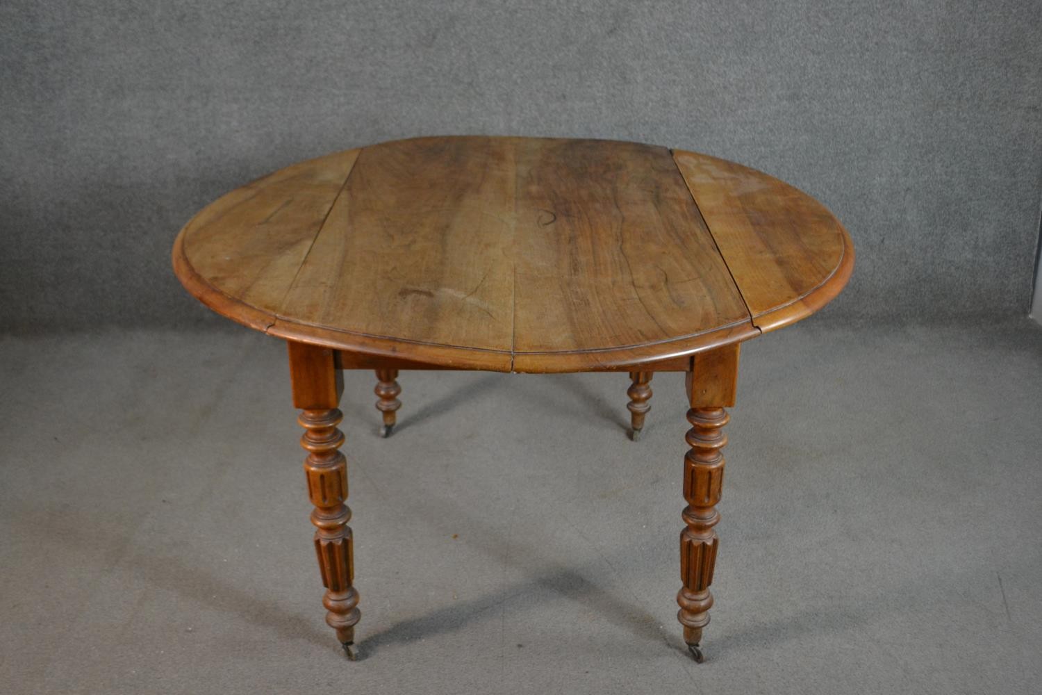 A Victorian figured walnut drop leaf dining table, the circular top with a moulded edge, on