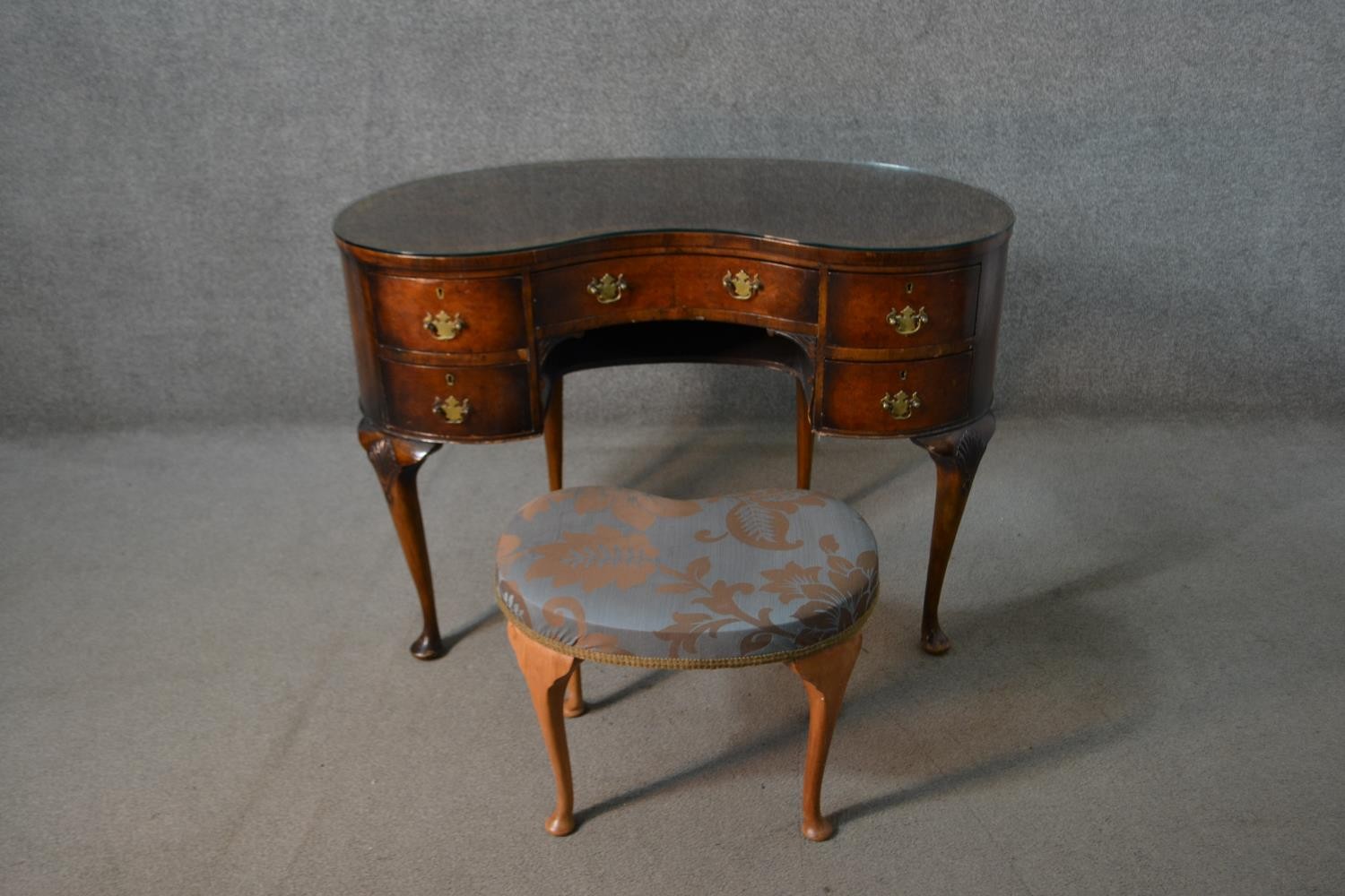 An early 20th century walnut kidney shaped dressing table, with a crossbanded top over an