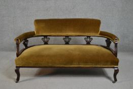 A late Victorian walnut two seater sofa, upholstered to the back and seat in golden velour, with